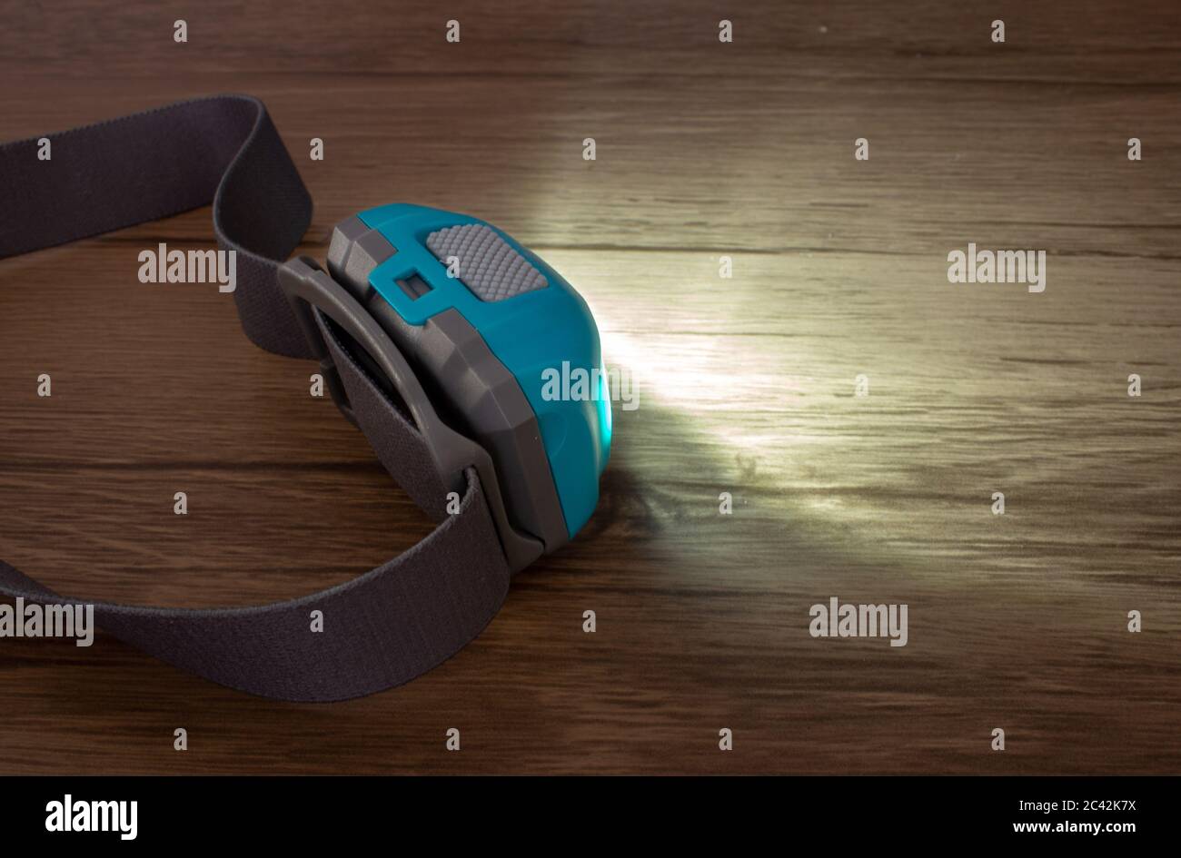 Teal headlamp turned on show the light beam on a wooden surface Stock Photo