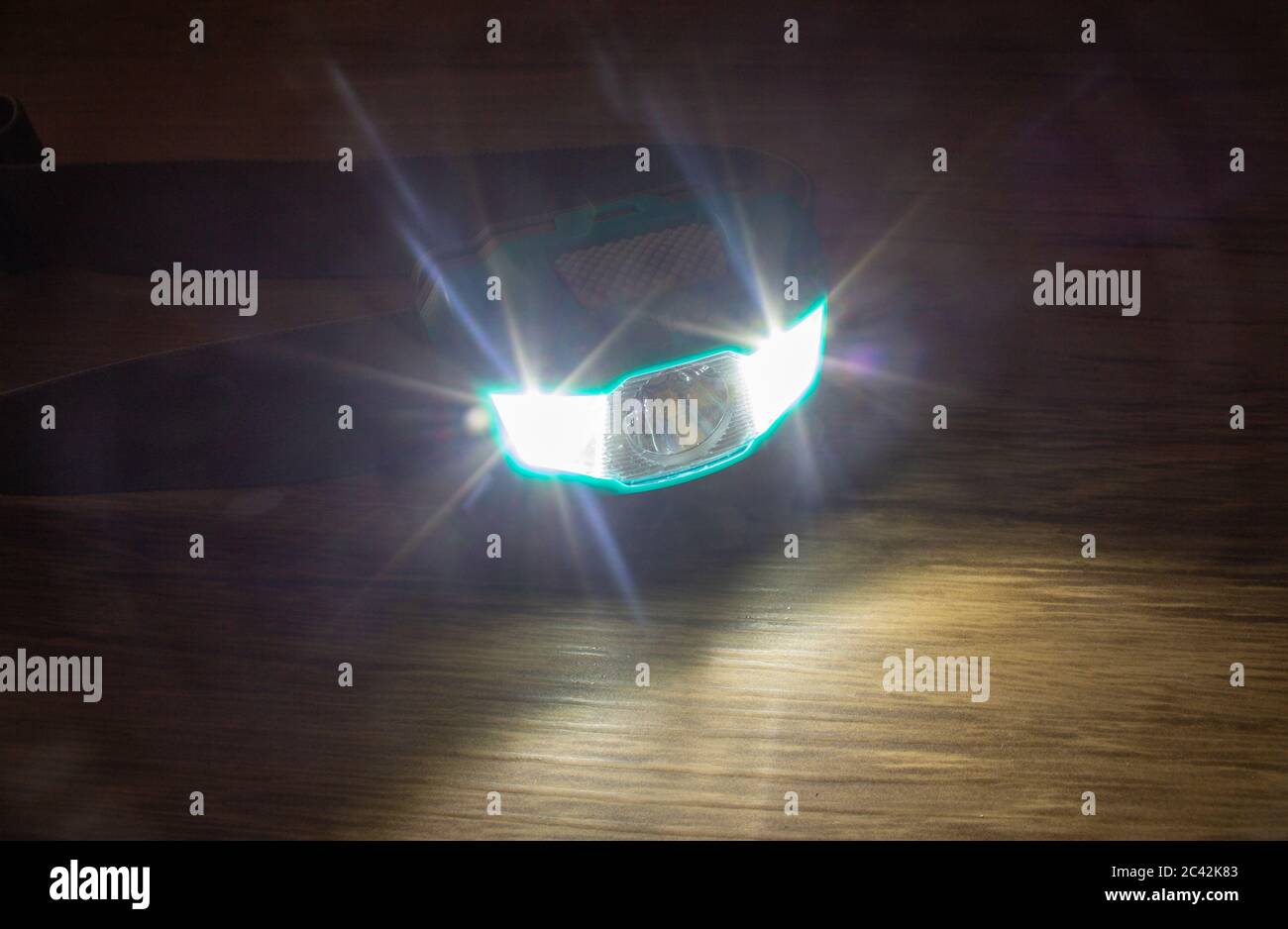 Teal headlamp turned on show the light bean on a wooden surface Stock Photo
