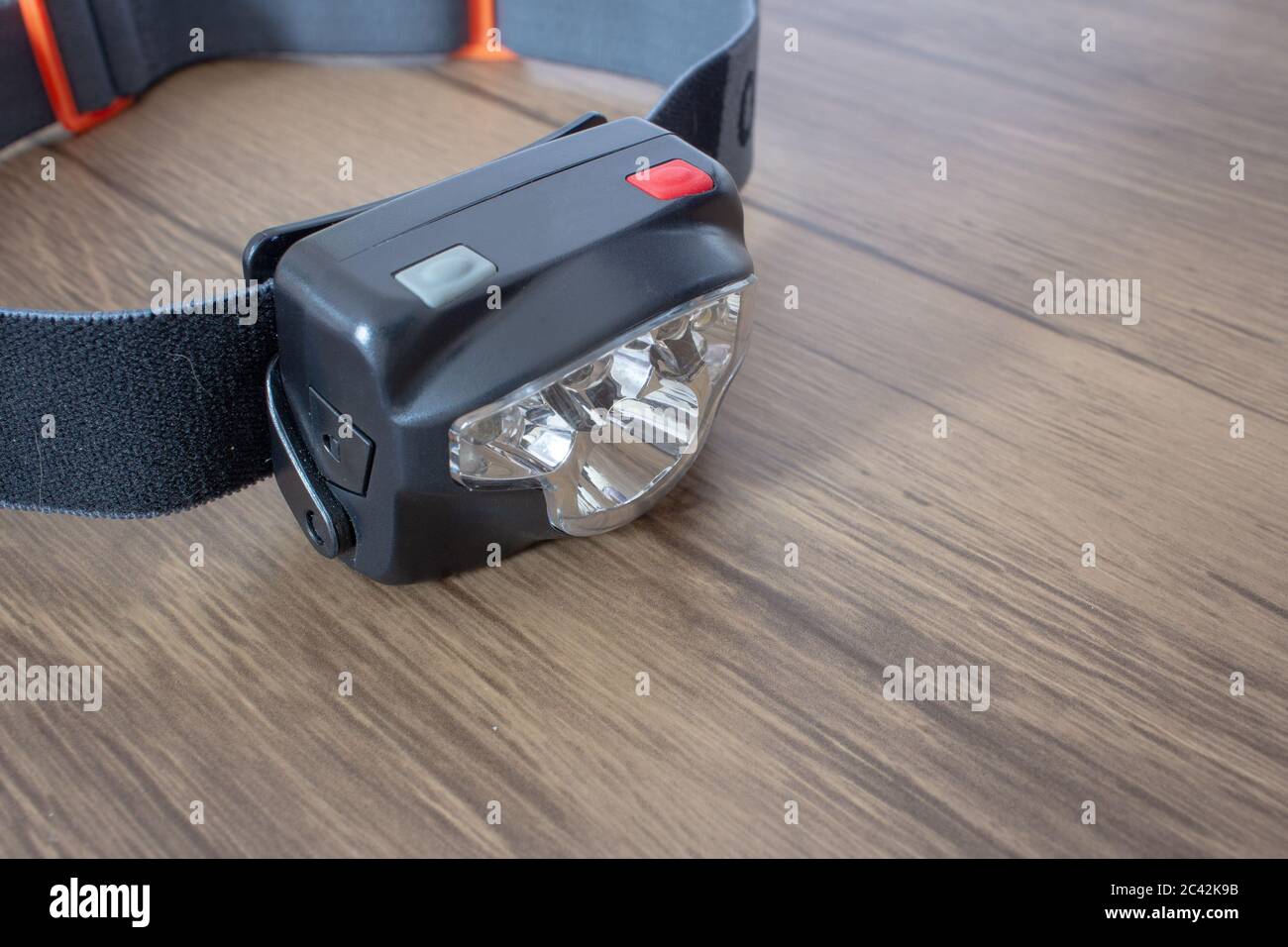 Black led headlamp turned off on a wooden table showing the elastic strap Stock Photo