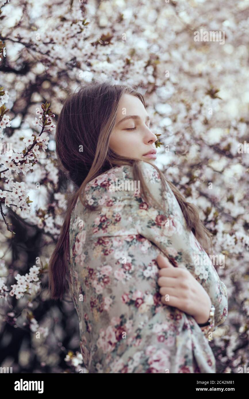 Young woman standing in front of cherry blossom tree Stock Photo - Alamy