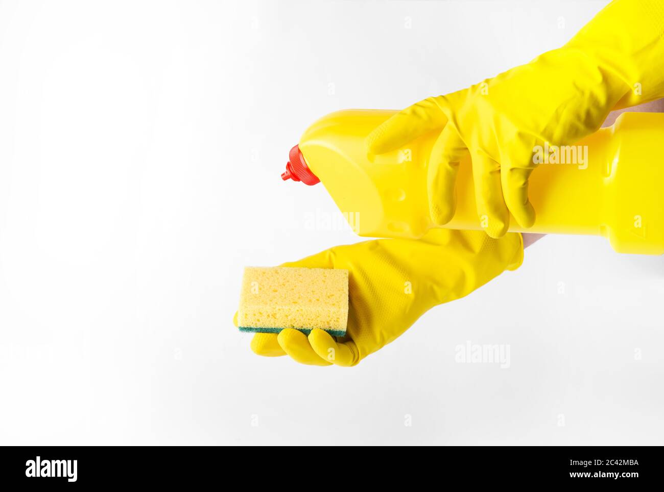 Hands in rubber gloves holding a plastic bottle with detergent and a ...