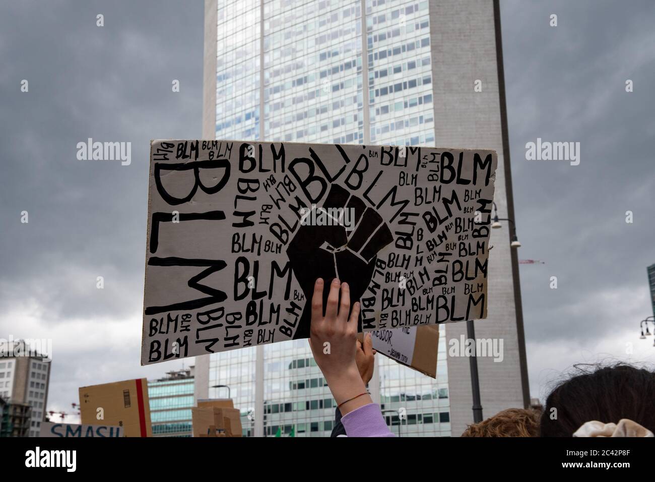 Hand of a young protester holding a sign with:'BLM and a raised fist' during the protest assembly in solidarity to BLM movement. Stock Photo
