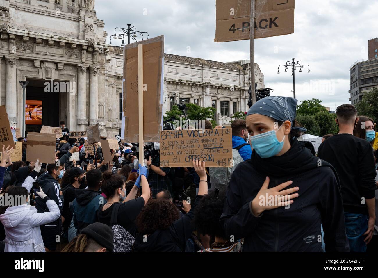 People with placards, one with the words 'Stop Violence' during the protest assembly in solidarity to BLM movement in front of Milan central station, Stock Photo