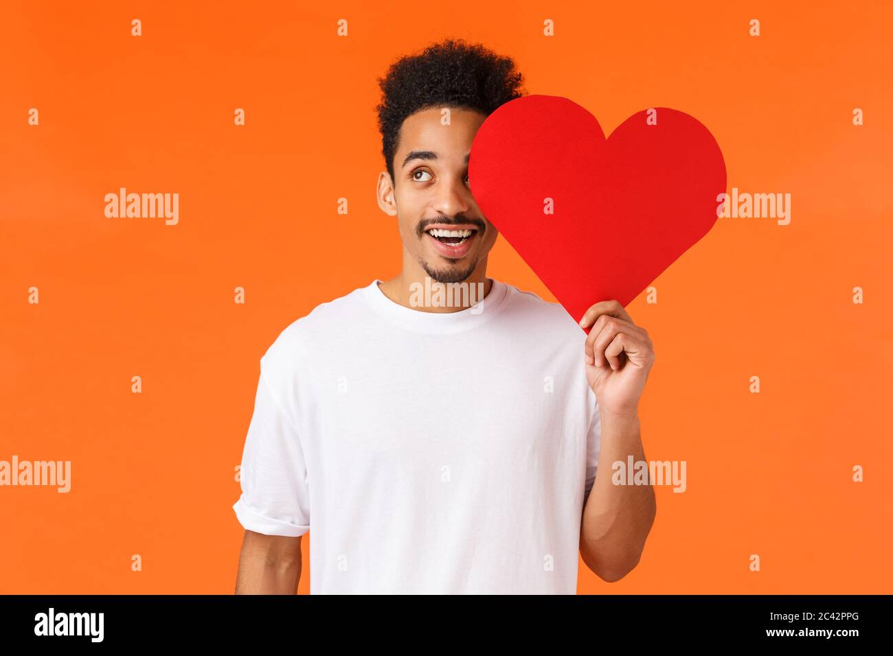 Dreamy handsome african-american guy found true love, giving valentines card to lover, looking upbeat up thoughtful, imaging perfect date, express own Stock Photo