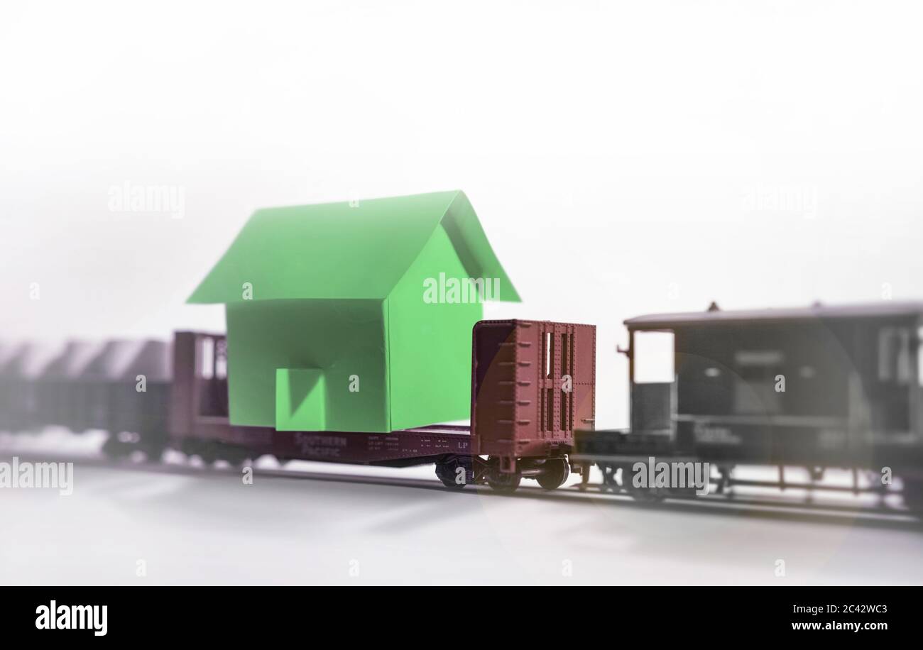 The surreal vision of a freight train carrying a house on one of its platforms. Copy-space, isolated. Stock Photo