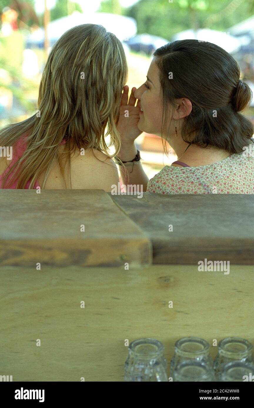 Two young women whisper something Stock Photo - Alamy