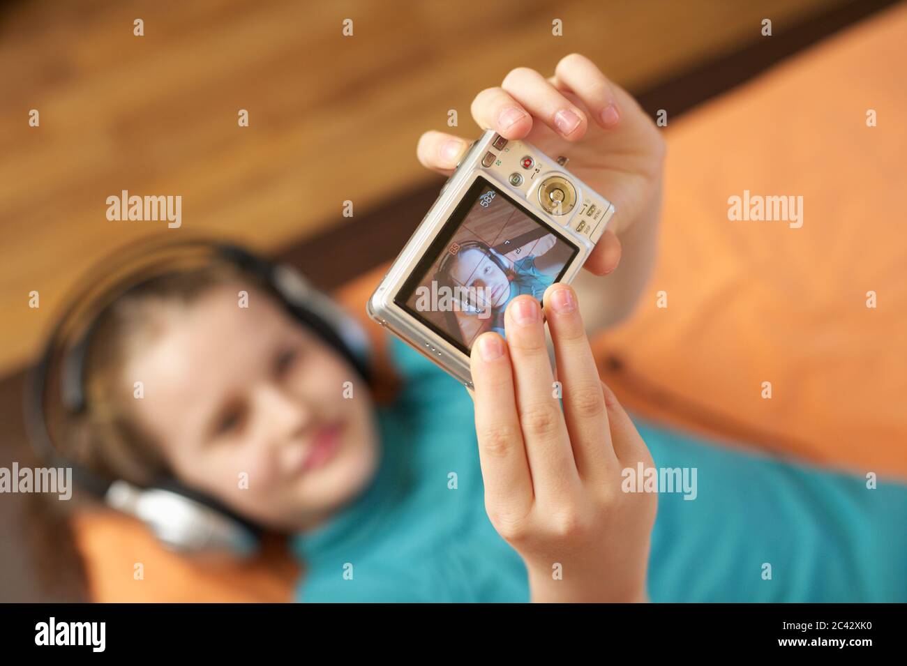 Girl with headphones photographs herself with a digital camera - technology - childhood Stock Photo