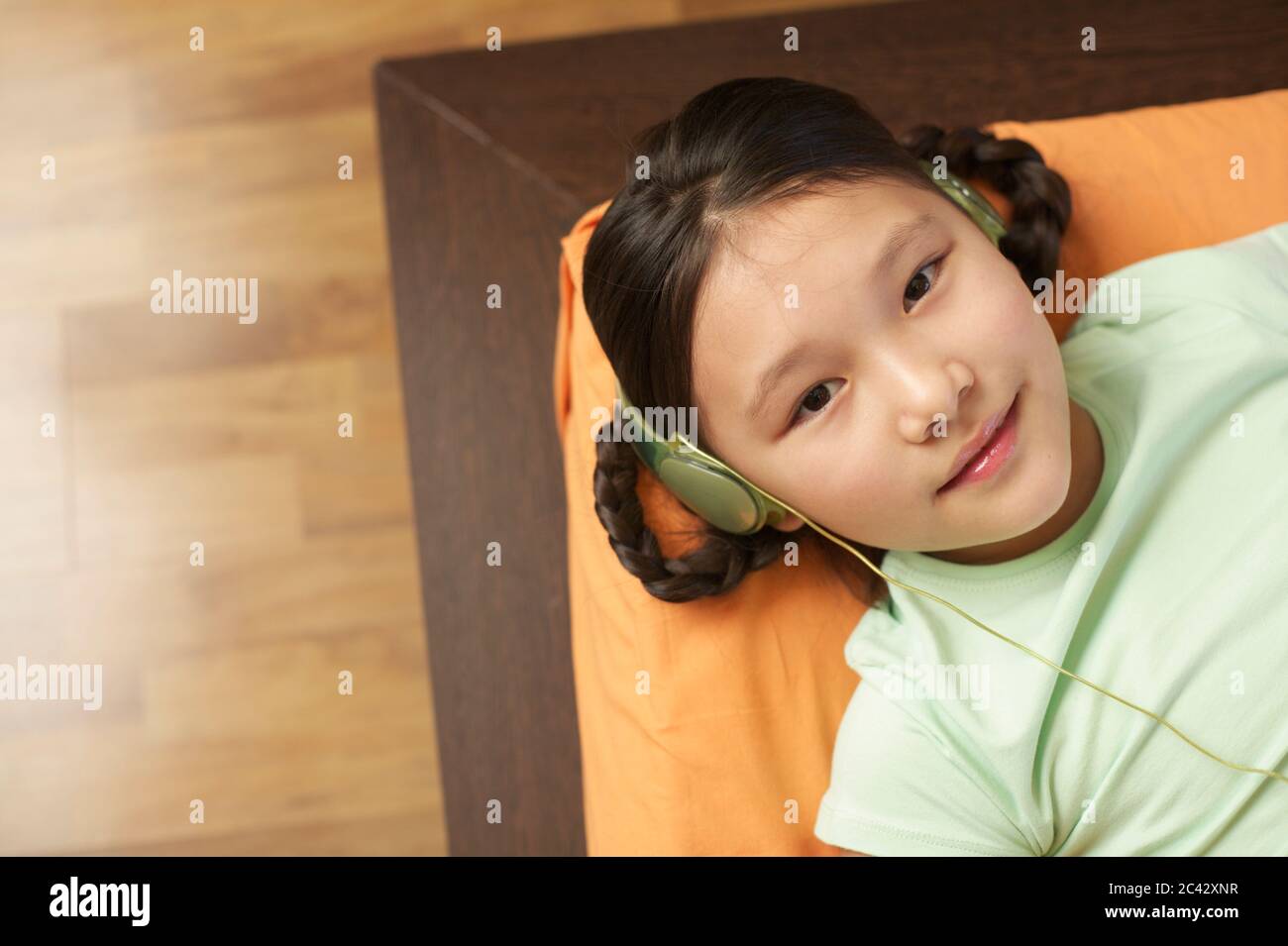 Girl with headphones on a couch - technology - childhood Stock Photo