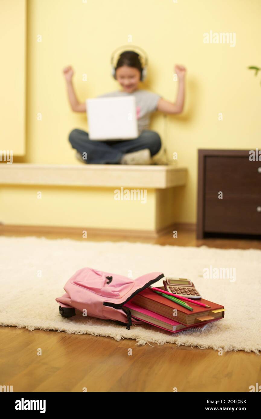 Girl sits on floor with headphones and laptop - technology - childhood Stock Photo
