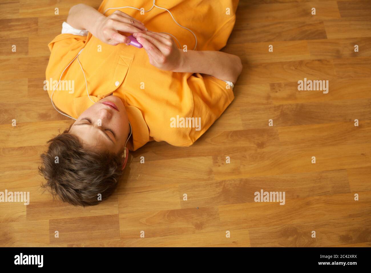 Little boy lies on the floor and listens to music with an MP3 player - youth Stock Photo