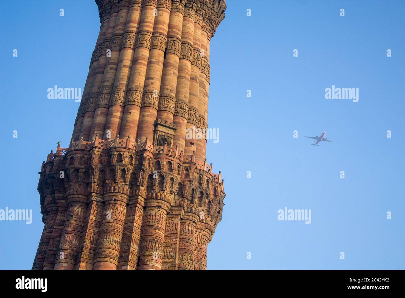 the Qutb Minar in Delhi India, there is plane pass through in the sky. Qutb Minar is a 73-metre (239.5 feet) tall tapering tower of five storeys Stock Photo