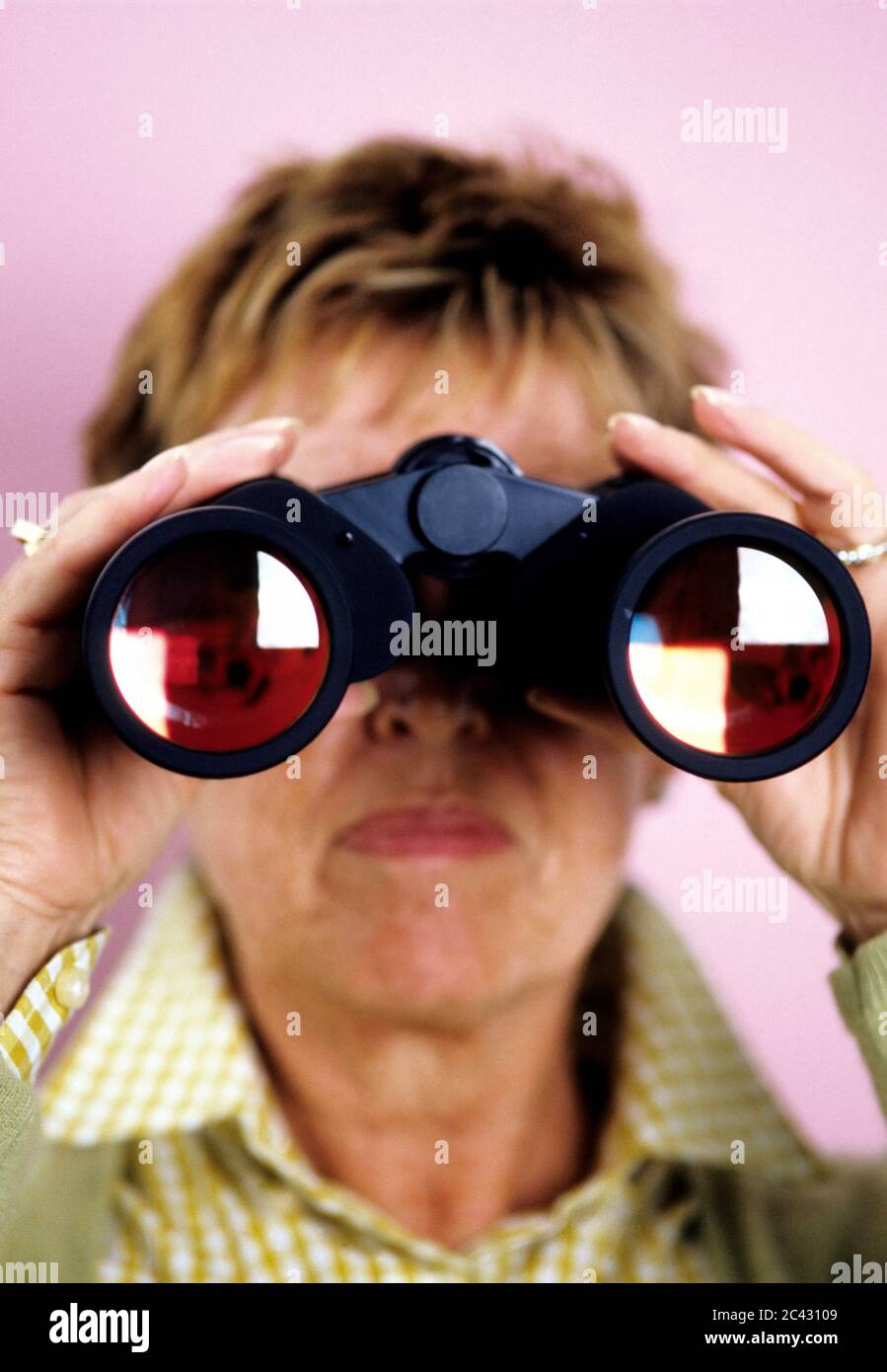 Elderly woman looks through binoculars - voyeurism Stock Photo