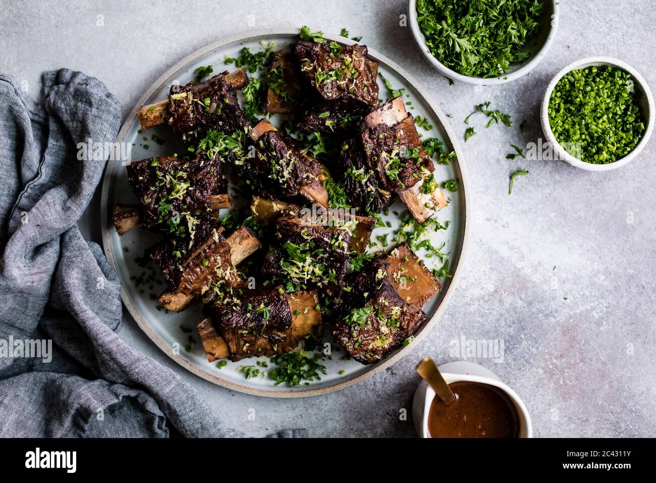 Roasted beef ribs with chopped parsley and chives on a plate. Stock Photo