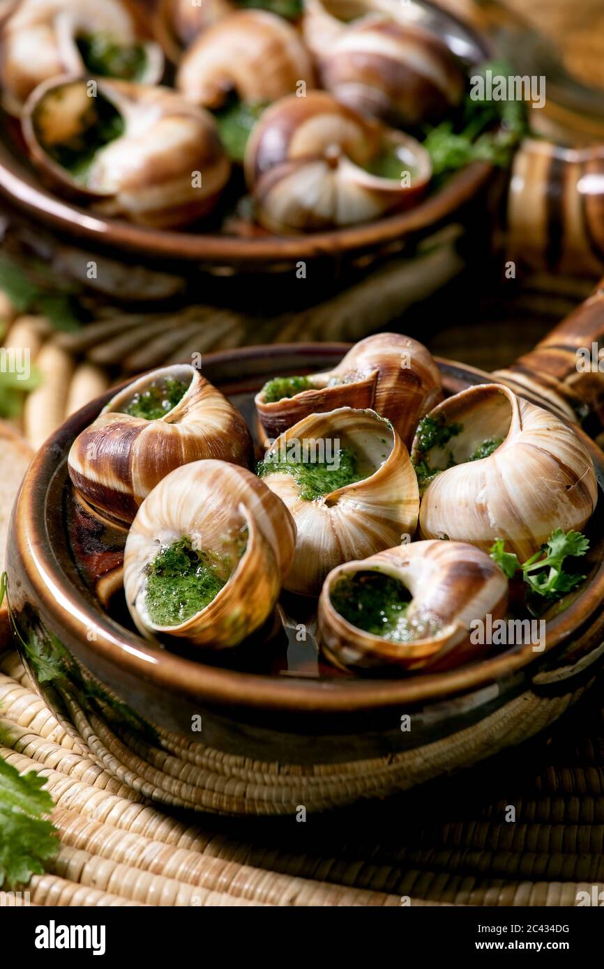Escargots de Bourgogne - Snails with herbs butter, gourmet dish, in two  traditional ceramic pans with coriander and bread on straw napkin. Close up  Stock Photo - Alamy