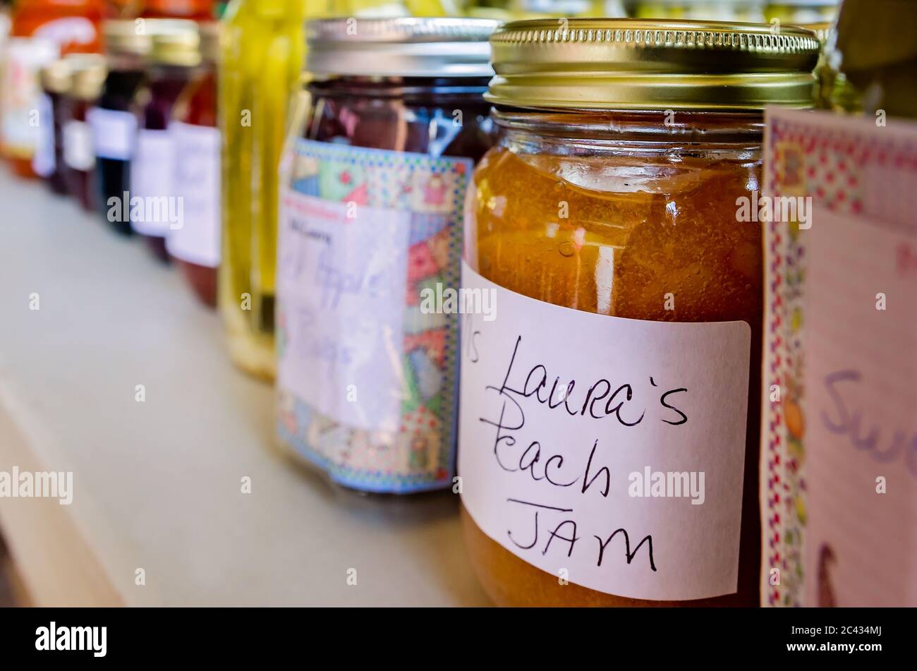 Peach jam, mock apple rings, and other fruit preserves are lined up at a vendor’s booth at the Clarksdale Farmers Market in Clarksdale, Mississippi. Stock Photo