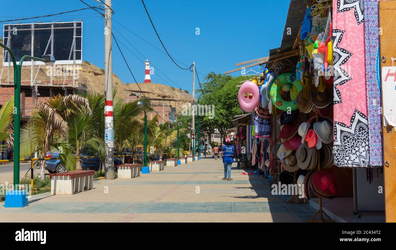 Mancora, Piura / Peru - April 10 2019: Tourists walking in the craft vendors area next to the main avenue of the town with the lighthouse in the backg Stock Photo