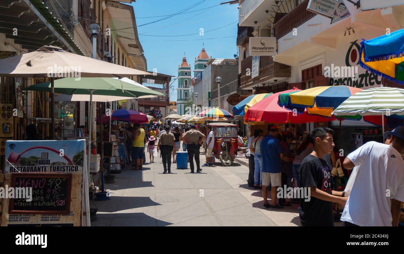 Catacaos, Piura / Peru - April 6 2019: Tourists walking on a street full of handicraft vendors in the center of town with the church in the background Stock Photo