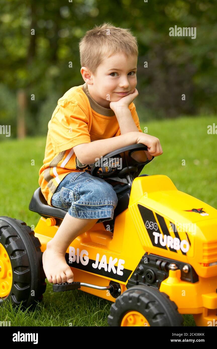 Boy on toy tractor Stock Photo - Alamy