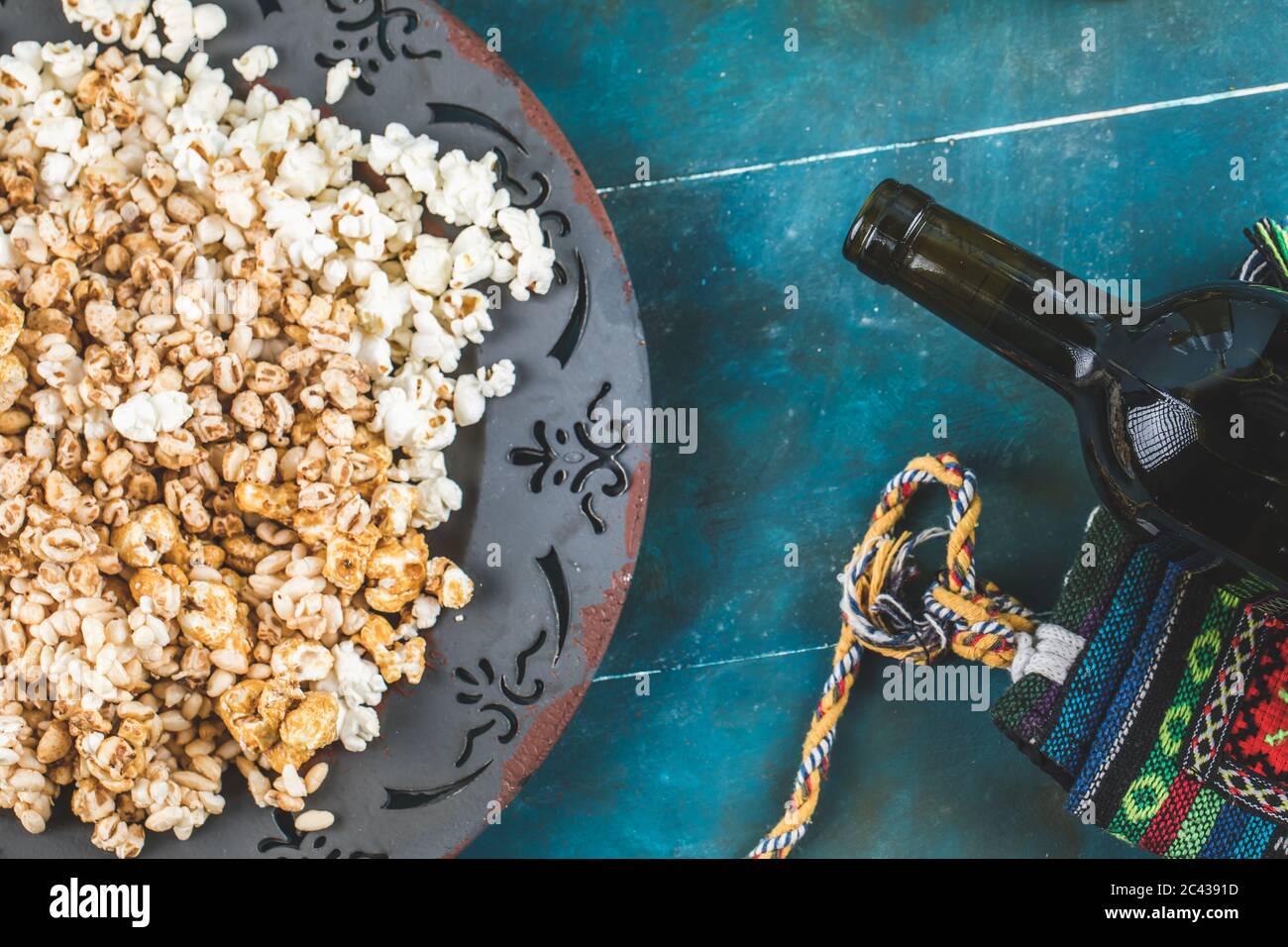 Popcorn , caramel corn and wheat corn snackes in a platter with a wine