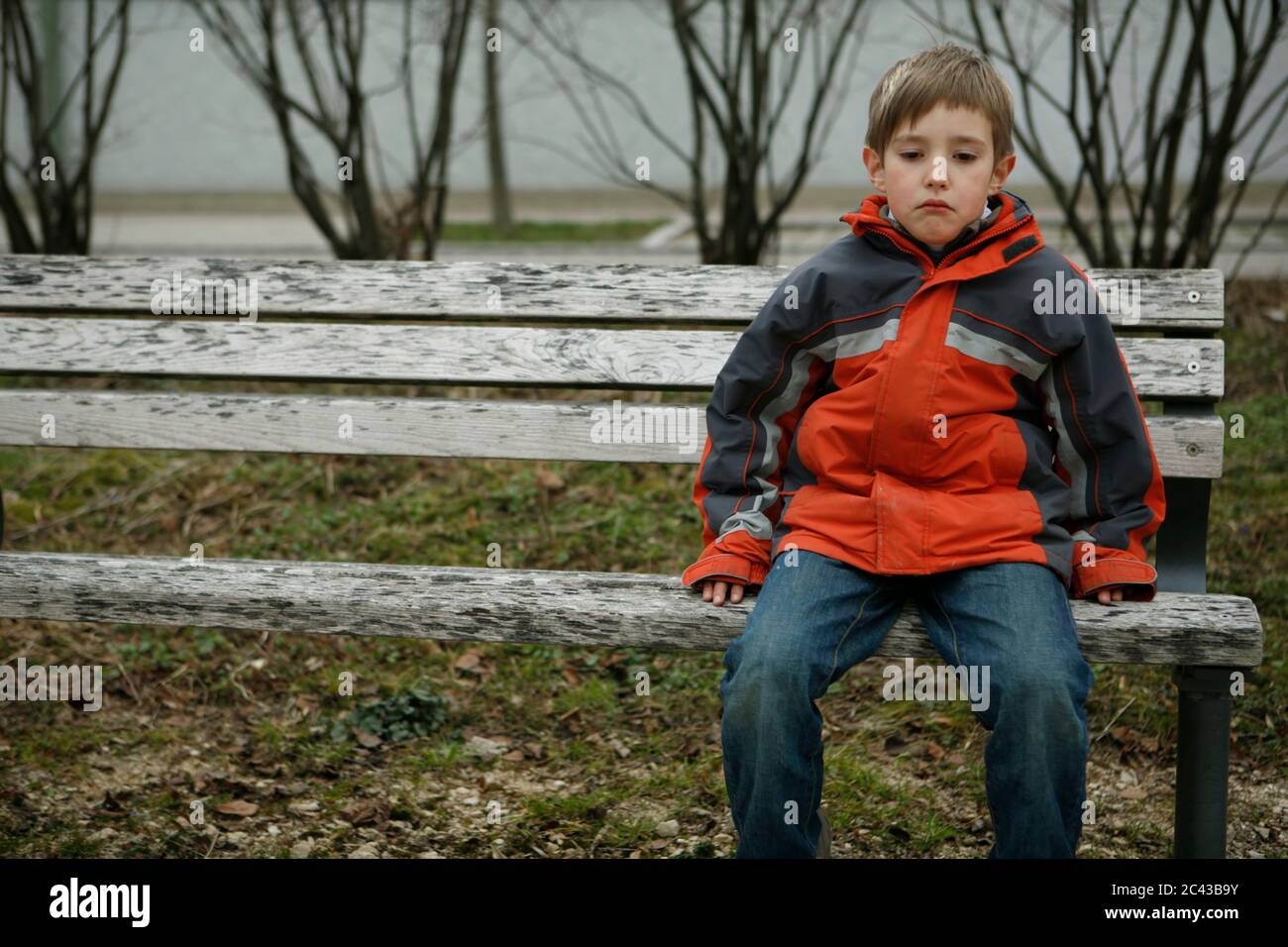 Sad boy is sitting on park bench Stock Photo - Alamy