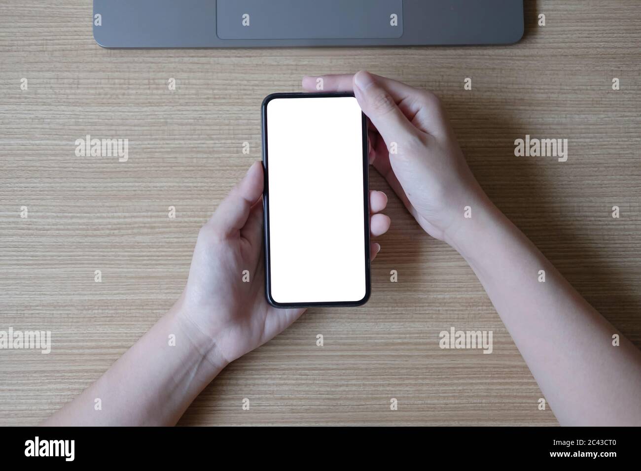 Woman hand holding smartphone with blank white screen on workplace ...