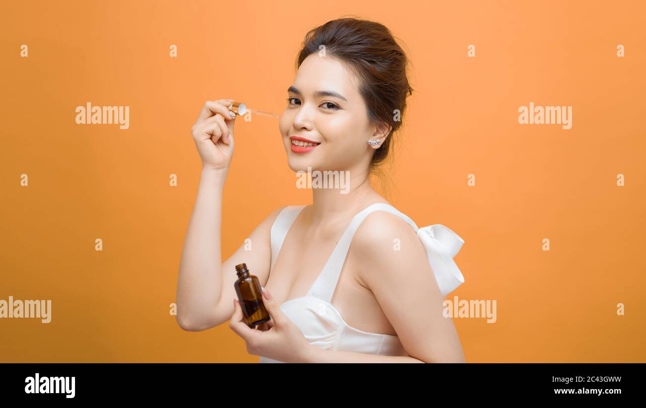 Closeup shot of cosmetic oil applying on young woman's face with pipette. Beauty therapy concept. Stock Photo