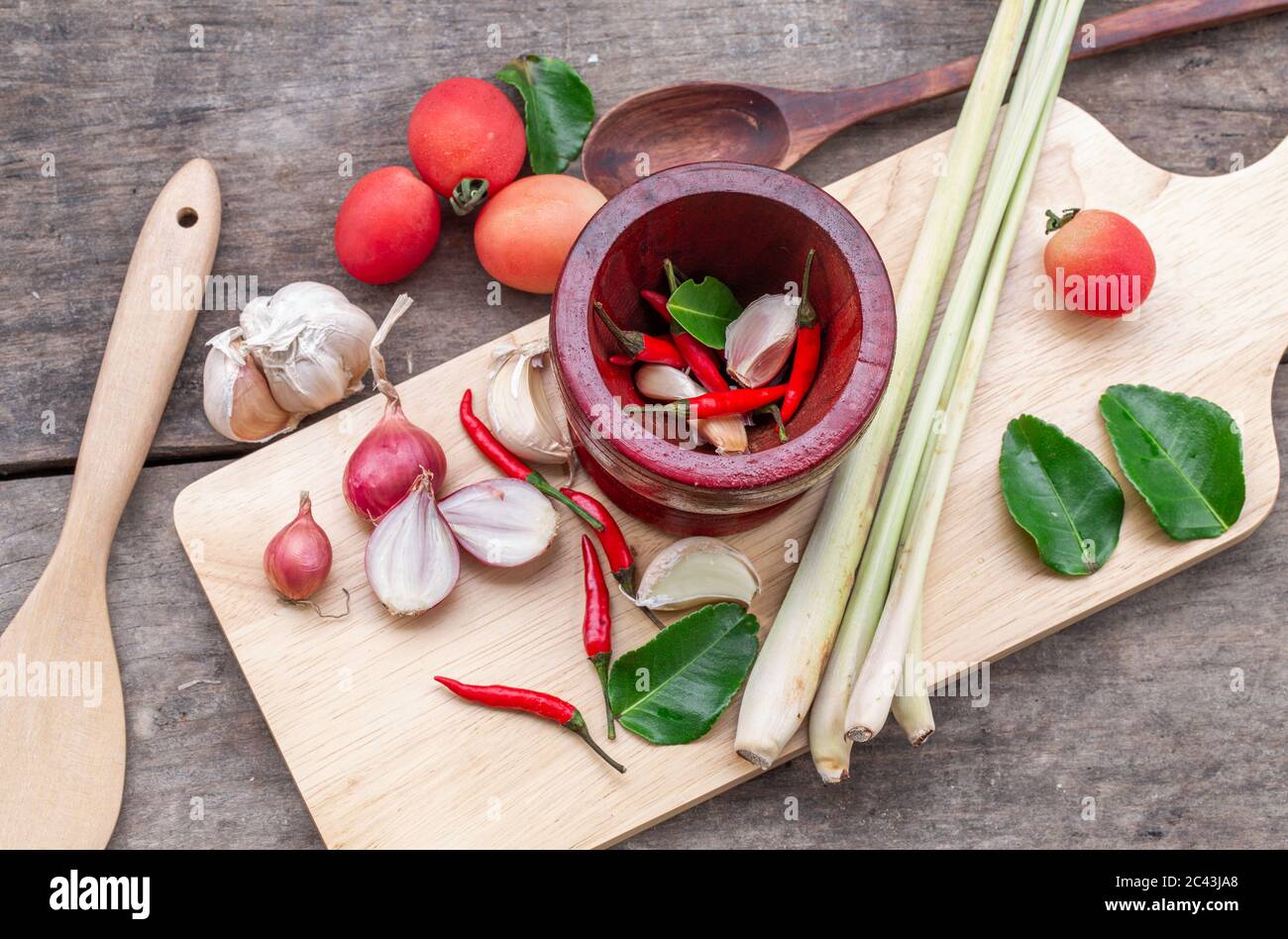 Fresh herbs and spices with wooden mortar on wooden background ...