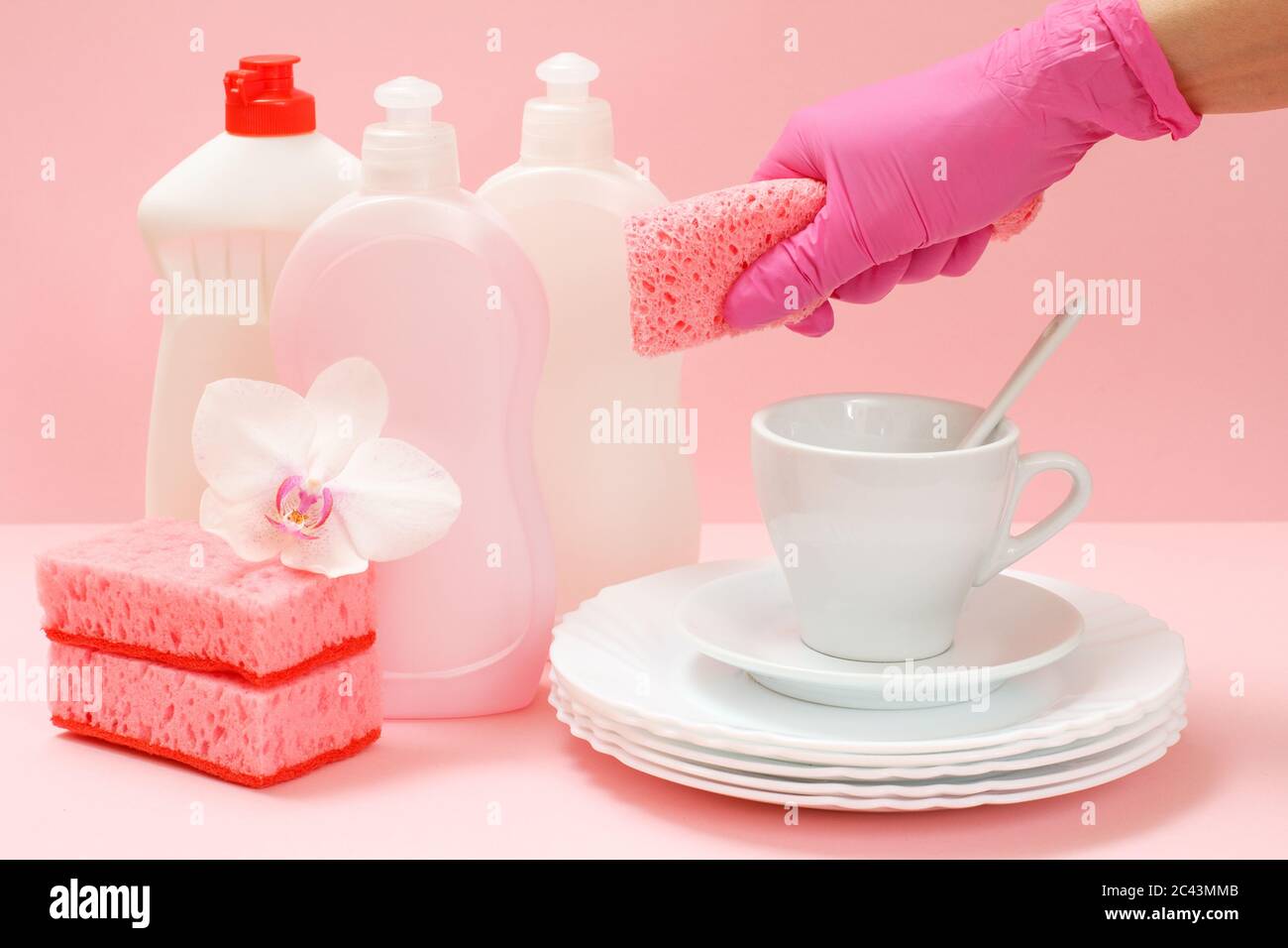 Woman's hand in a rubber protective glove with a sponge, white plates ...