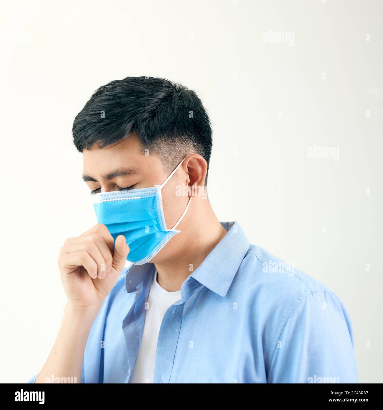 Asian man wearing surgical face mask coughing in subway station with crowded people walking pass. Wuhan coronavirus (COVID-19) outbreak prevention Stock Photo