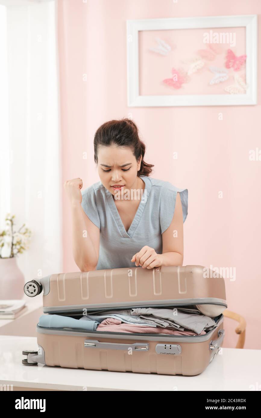 Woman trying to fit all clothing to packing her suitcase before vacation Stock Photo