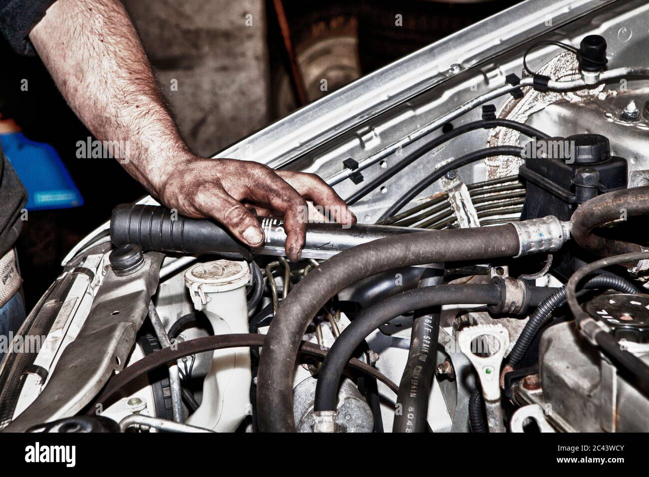 Auto mechanic on the open hood of a car Stock Photo