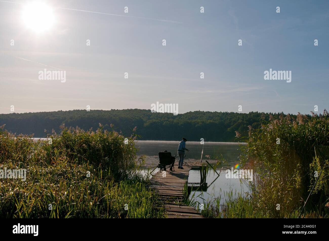 fisherman with fishing rods at sunrise on the lake Stock Photo