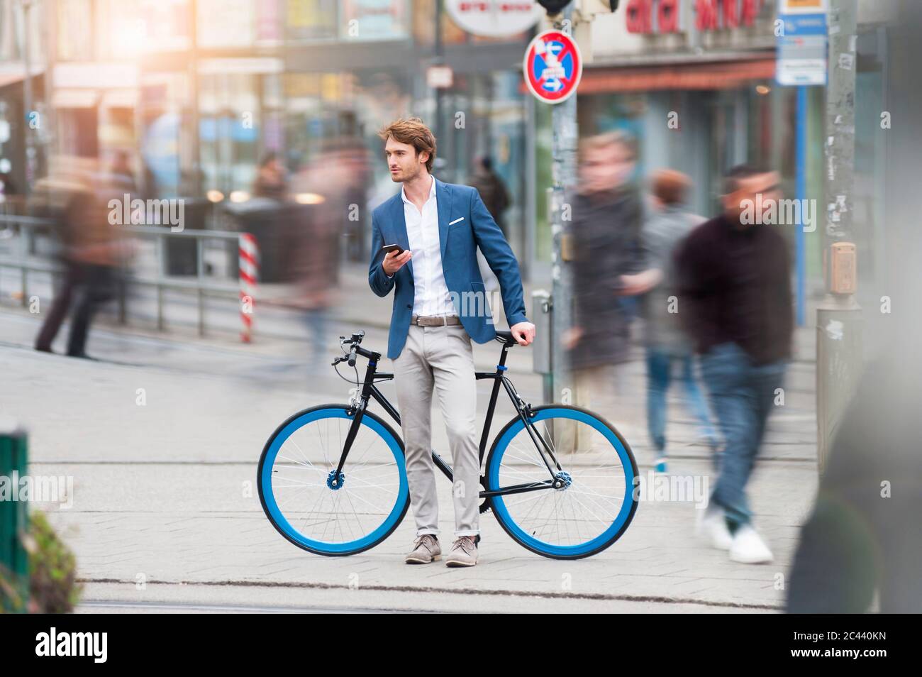 Portrait of young businessman with bicycle and smartphone waiting in the city Stock Photo