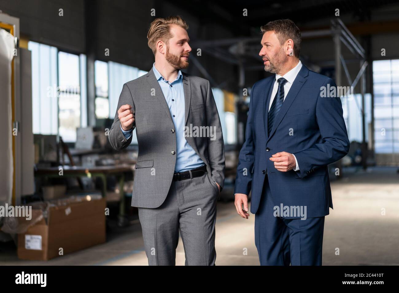 Two businessmen walking and talking in a factory Stock Photo - Alamy