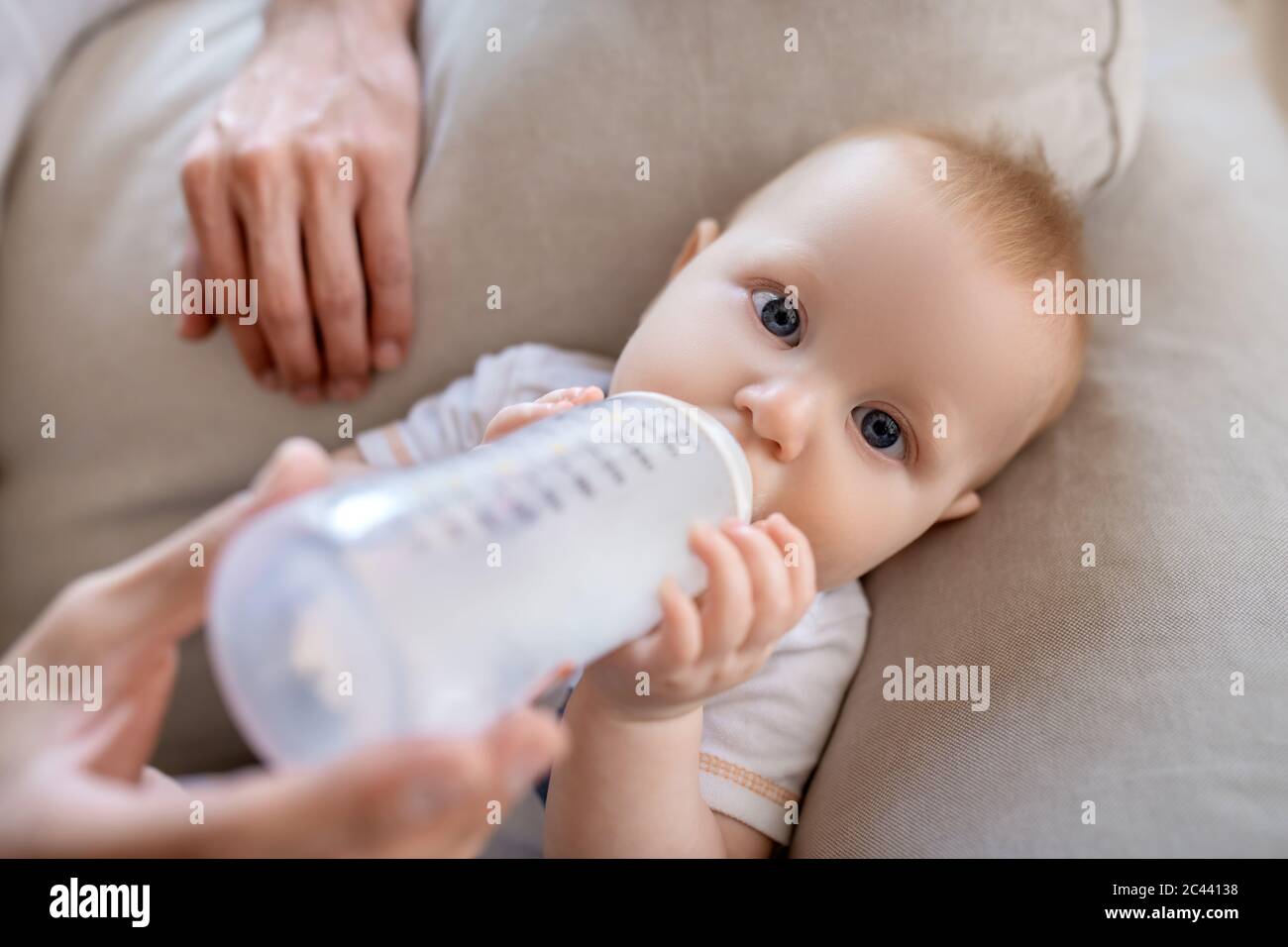 Fathers hands holding the bottle with milk for the baby Stock Photo