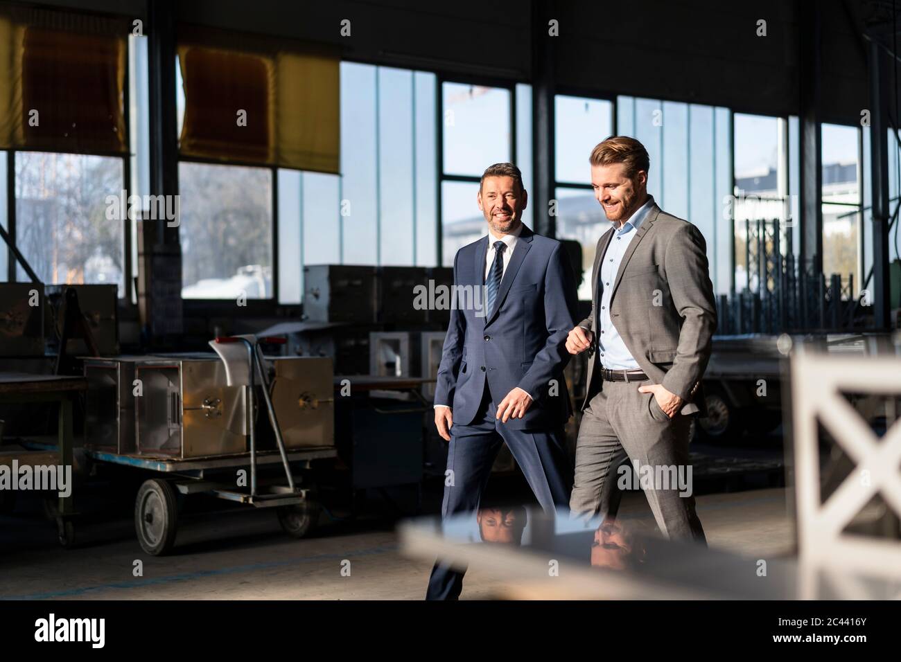 Two smiling businessmen walking in a factory Stock Photo - Alamy