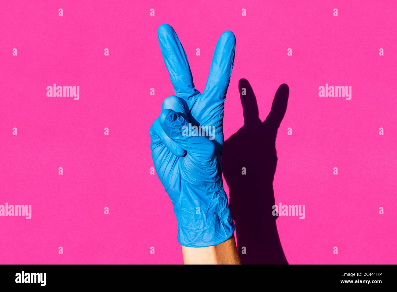 Hand of woman wearing latex glove making V sign Stock Photo
