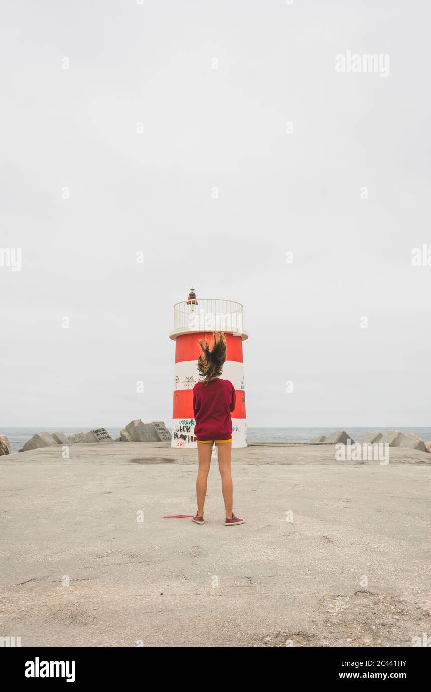 Teenage girl standing at a little lighthouse in Nazare, Portugal Stock Photo