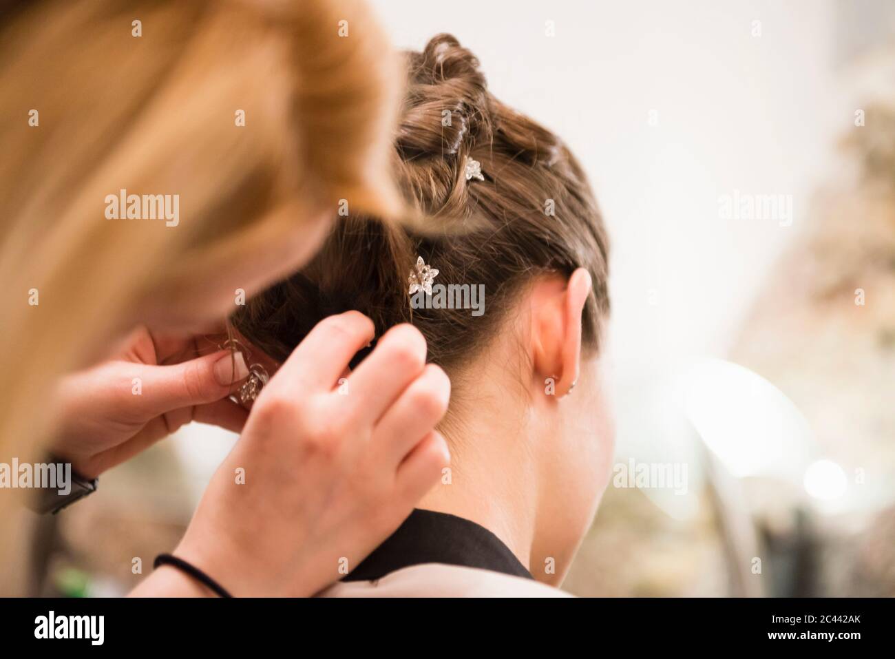 Close-up of bridesmaid styling bride hair at home Stock Photo