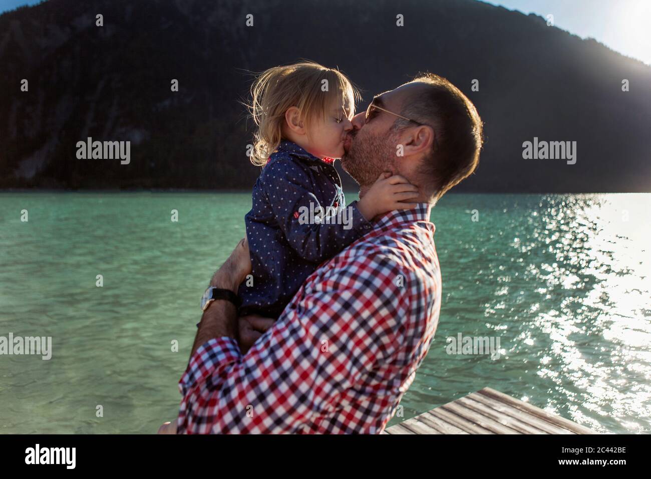 Father and daughter kissing against mountain and lake at Achensee, Tyrol State, Austria Stock Photo