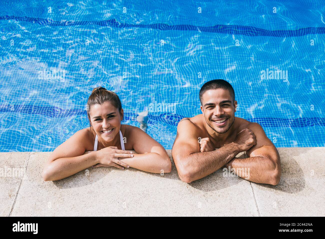 Smiling young couple standing in swimming pool Stock Photo