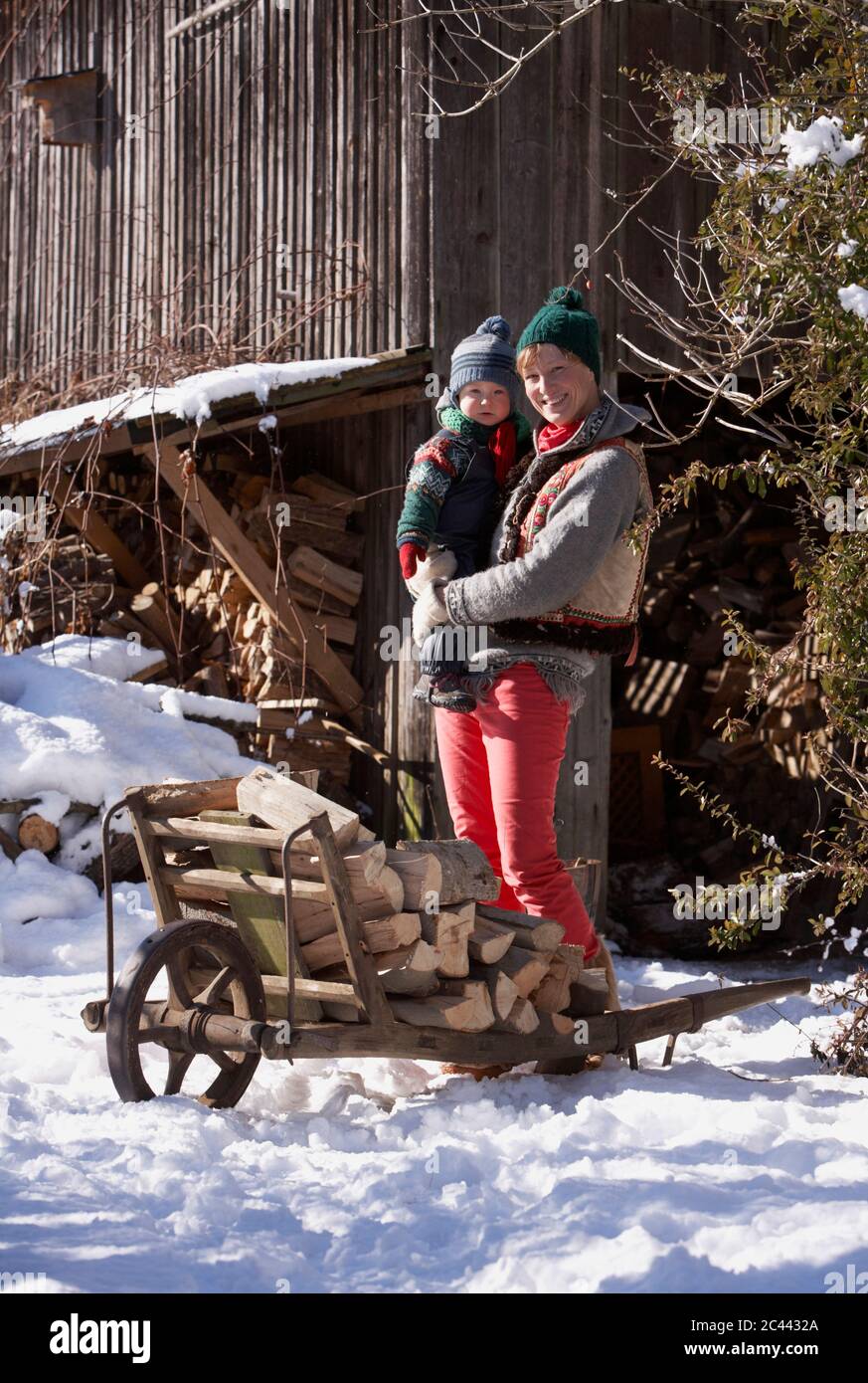 Mother and son with a wheelbarrow full of firewood in the snow Stock ...