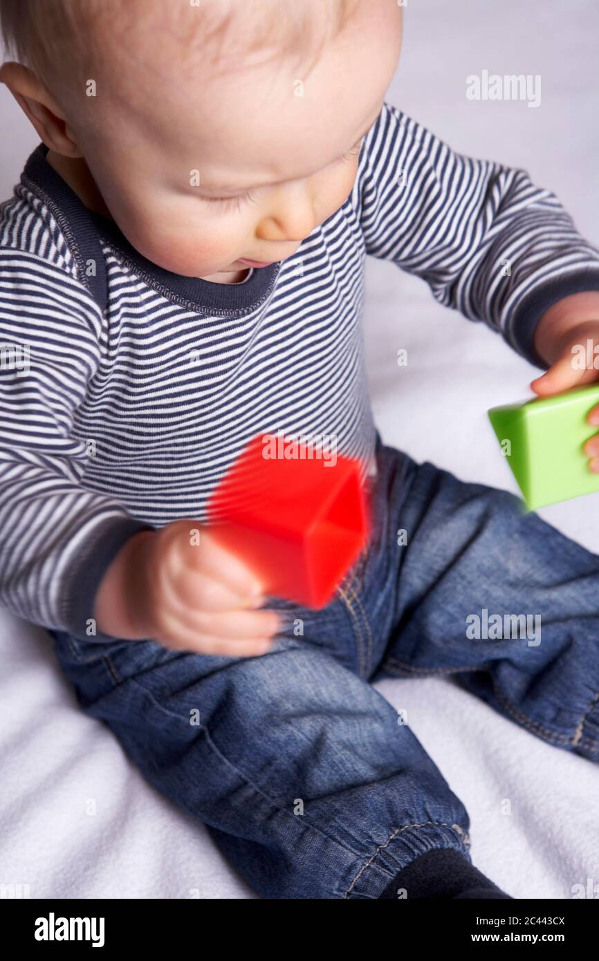 Baby on a blanket plays with building blocks Stock Photo
