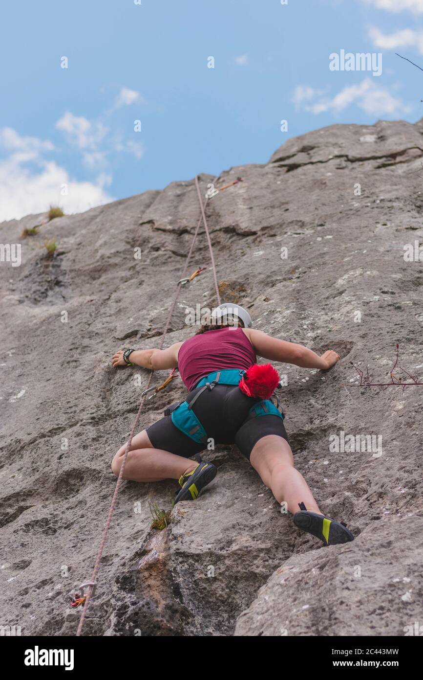 Young woman rock climbing against sky Stock Photo