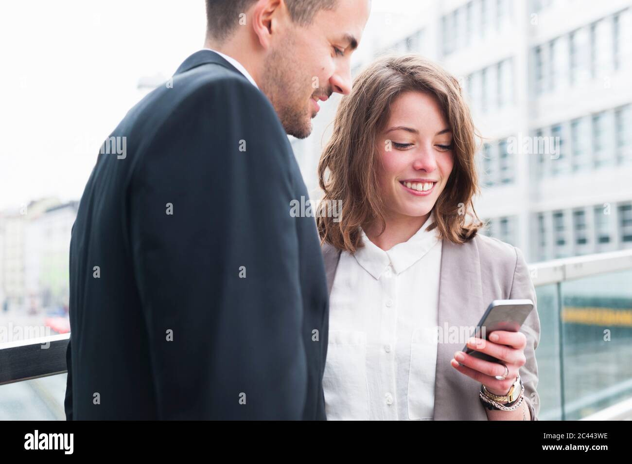 Business couple using smart phone outside office building Stock Photo