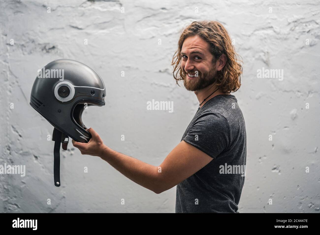 Young man holding helmet and looking at camera Stock Photo - Alamy