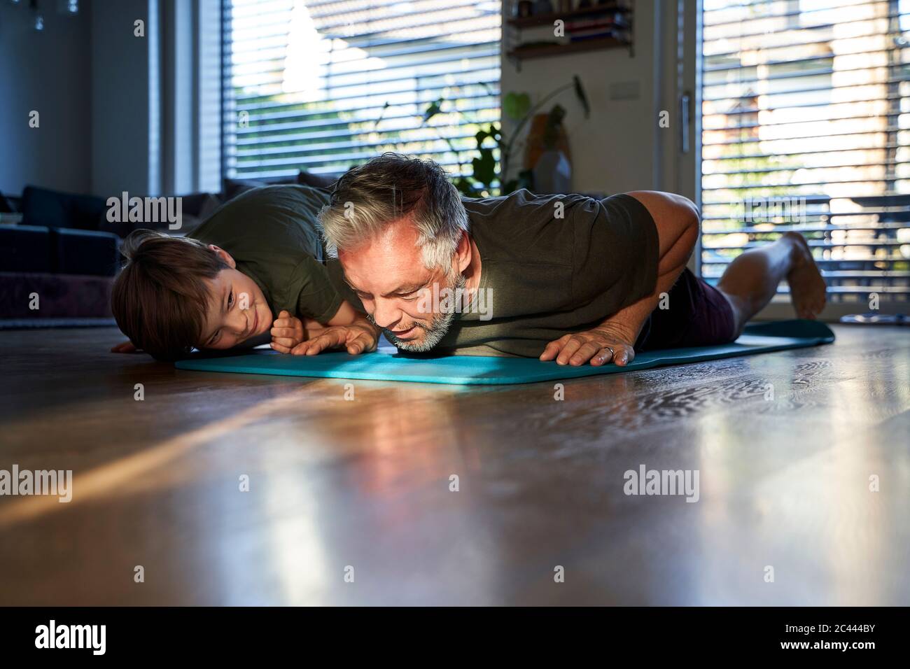 Boy watching his father doing a home workout Stock Photo