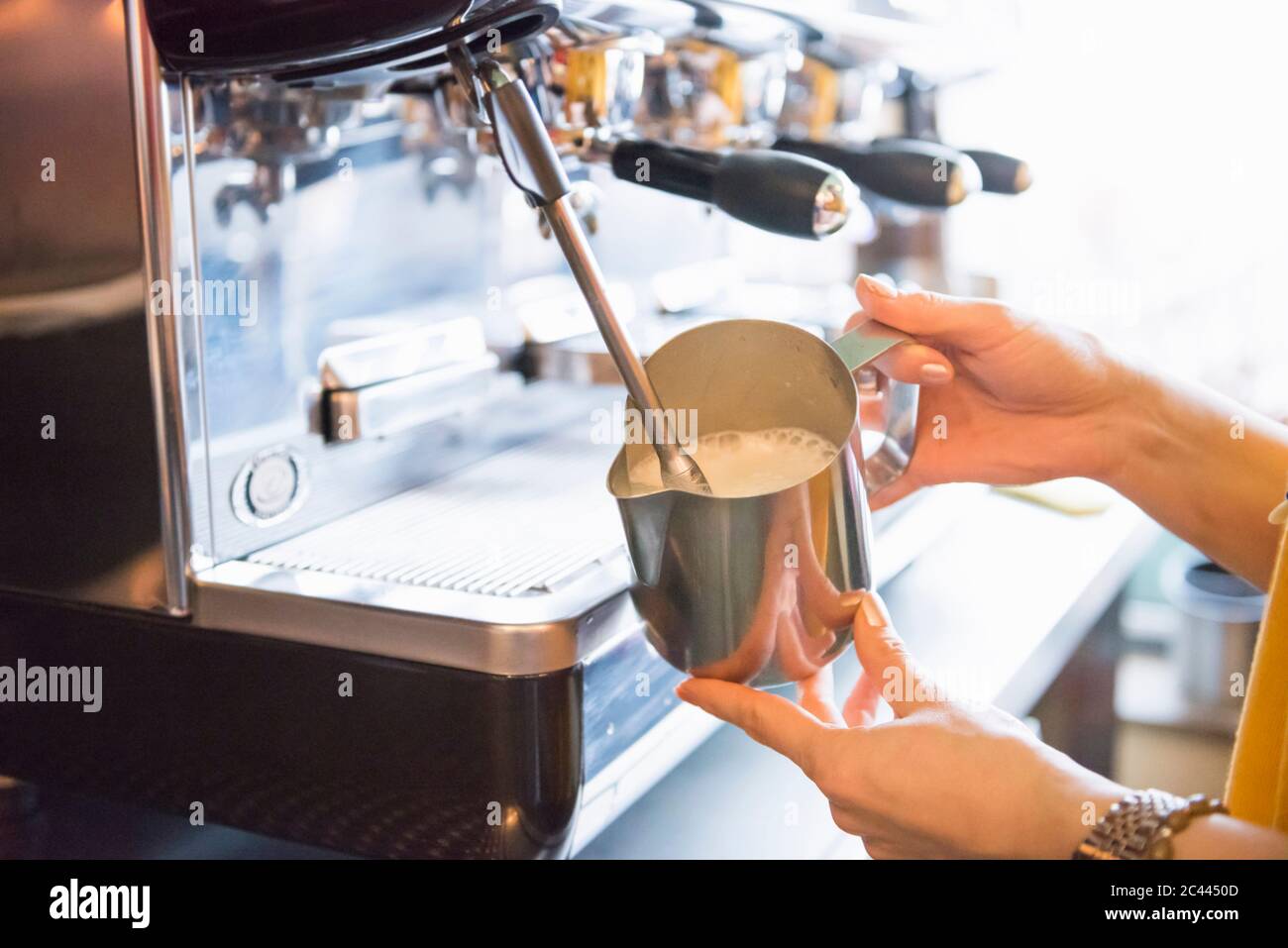 Hands of female barista frothing milk 
