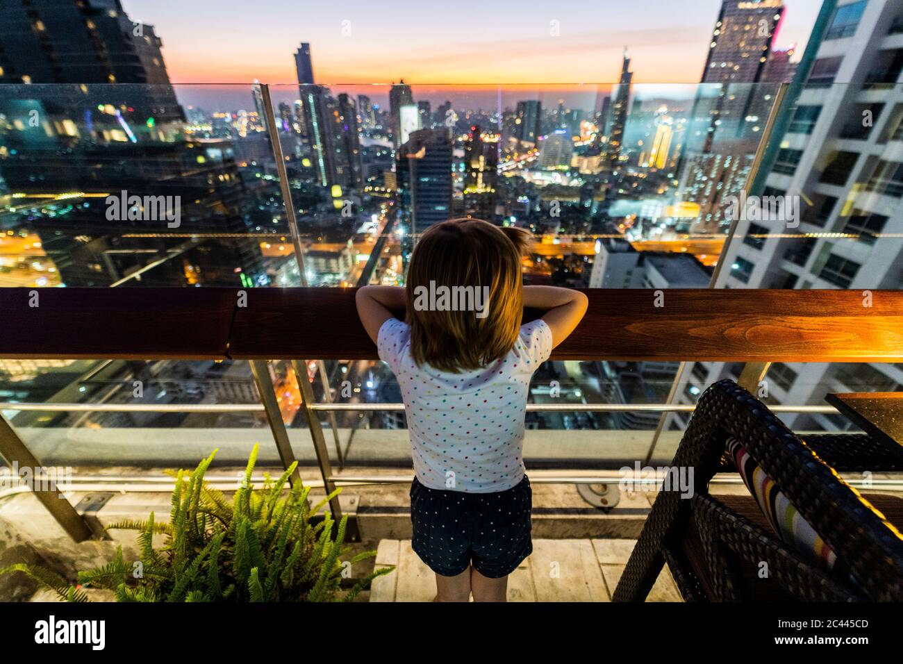 Girl looking at skyline of Bangkok at dusk, Thailand Stock Photo