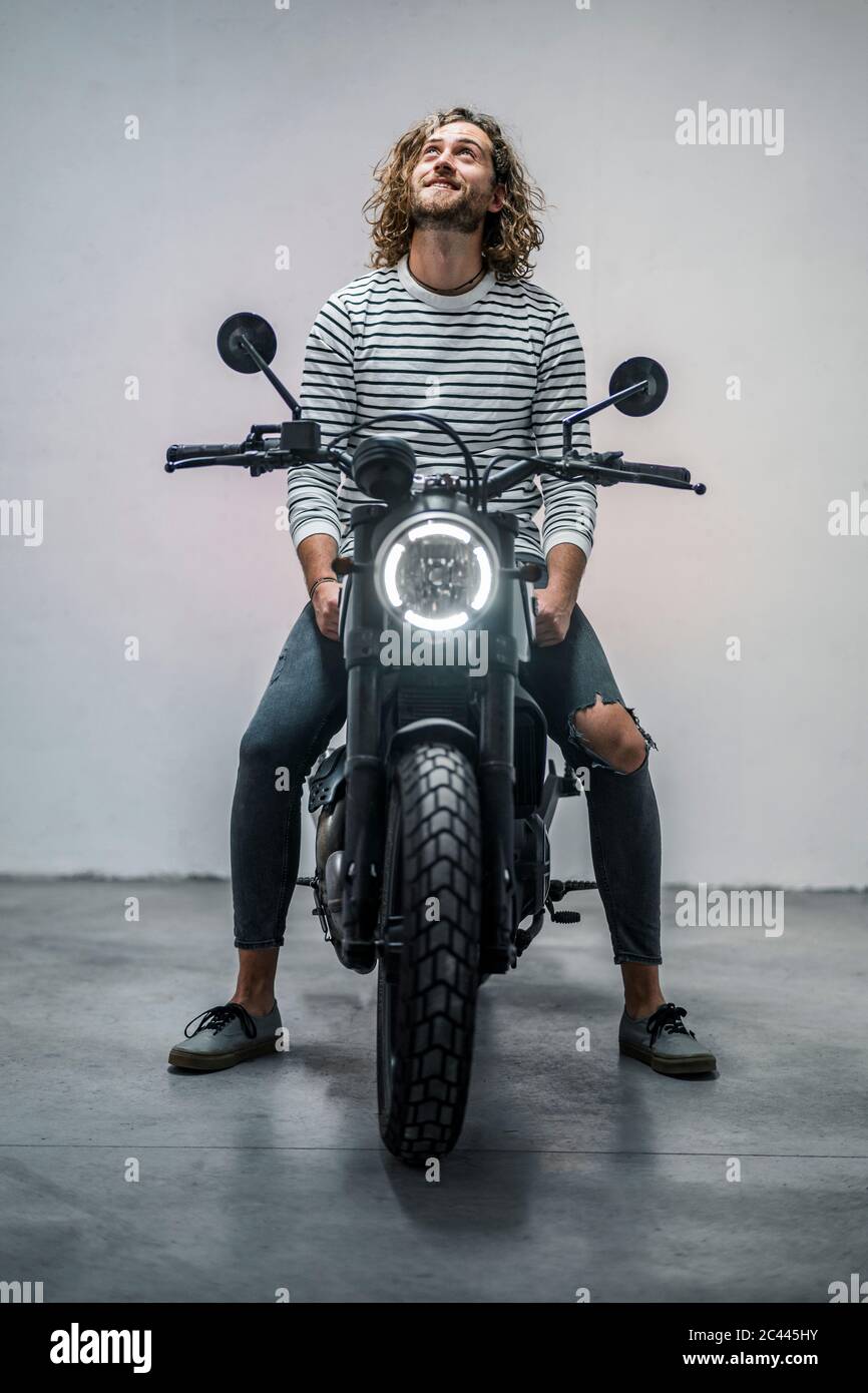 Young man looking up sitting on motorcycle Stock Photo